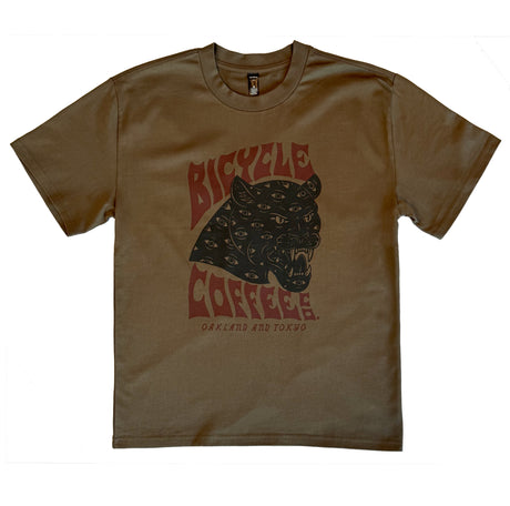 Brown T-shirt featuring a bold graphic of a black panther head covered in eyes, with red ‘Bicycle Coffee’ text and ‘Oakland and Tokyo’ printed below.